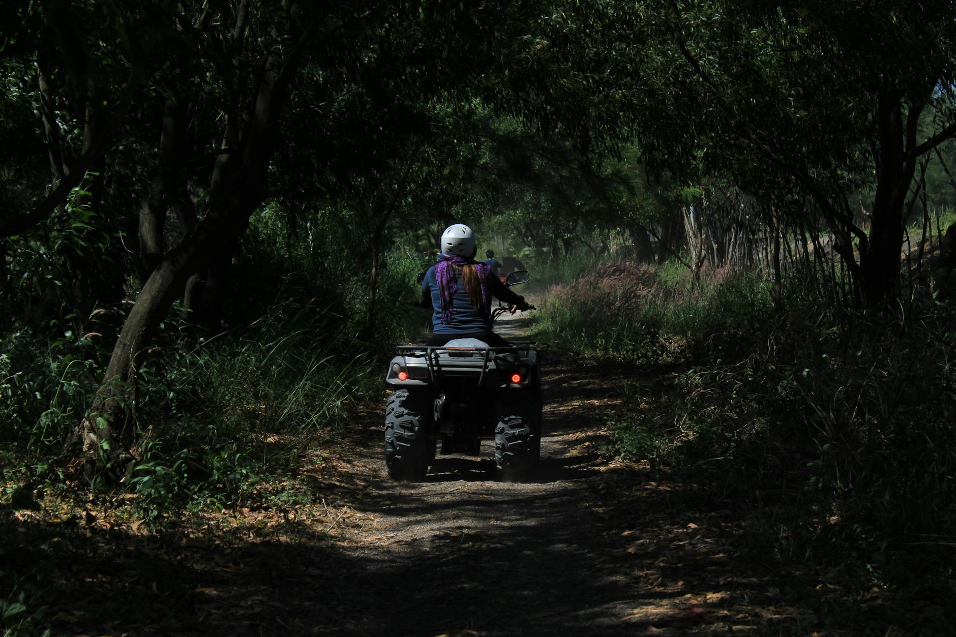 man riding black atv on dirt road